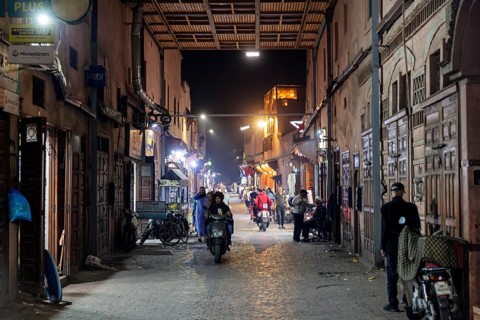 Night view of a busy alley with people, shops and alleyway lights in an old town