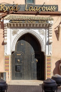 A traditional riad with a richly decorated entrance gate and Moroccan design elements in warm