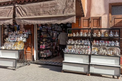 A market stand in Marrakech with a selection of shiny teapots and plates on display