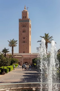 The Koutoubia Mosque in Marrakech, surrounded by palm trees and a sparkling fountain, visited by