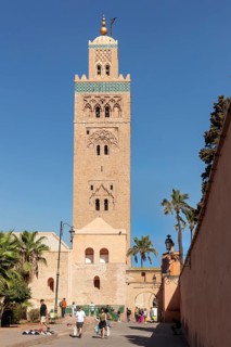 Frontal view of Koutoubia Mosque with passers-by and palm trees in the foreground