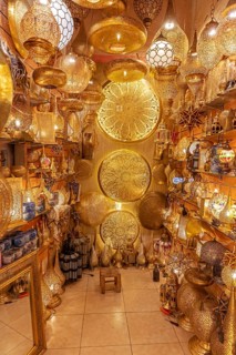 A room with numerous golden, artfully designed Moroccan lamps
