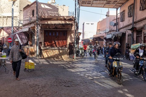 Busy street with motorcyclists and pedestrians in a sunny neighborhood