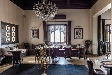 Elegant restaurant dining room with chandeliers, black and white paintings and large windows