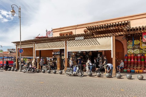 Lively market street with kiosks, traffic and people in sunny weather