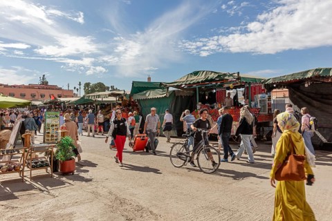 Lively market with people, bikes and stalls under a blue sky