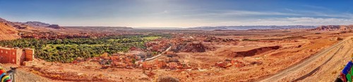 Wide desert landscape with oasis and village under a clear sky