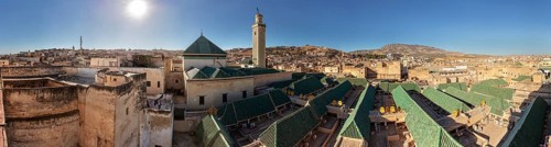 Extensive view of an old town with prominent green roofs and minaret