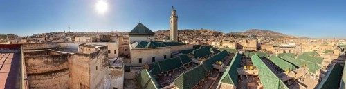 Panoramic view of an old town with a distinctive minaret and green roofs