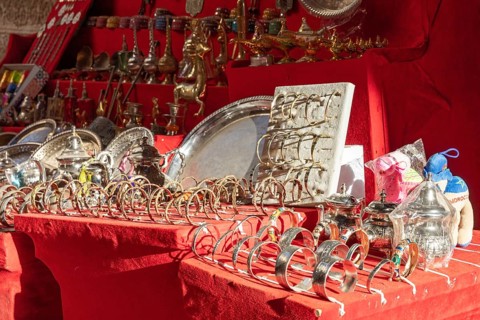A market stall full of shiny silver and jewelry on red fabric