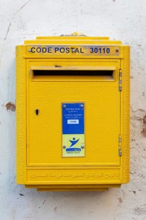 Yellow letterbox on a wall with Arabic and French letters