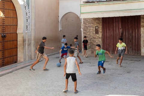 Children play soccer in a narrow alley. Carefree summer atmosphere