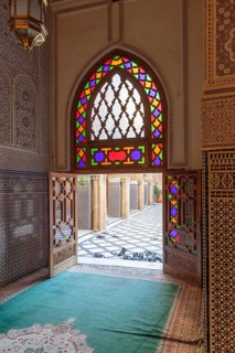 A sumptuous interior with a colorful stained glass window that throws light into the room in