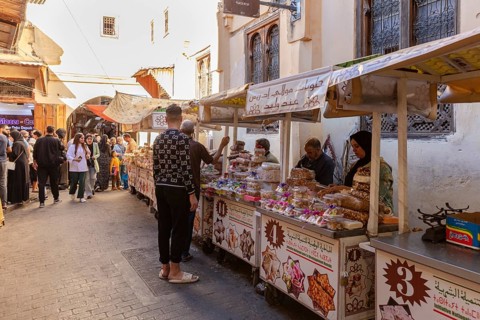 Market scene with people and various food stalls in an old town street