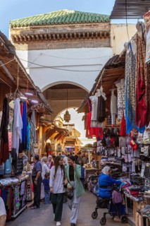 Bustling market corridor with numerous clothes and fabrics under an archway