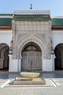 A richly decorated Islamic building with a central well, surrounded by mosaics and Islamic