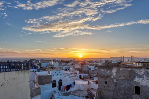 City panorama at sunrise with warm sky tones and scattered clouds over flat buildings