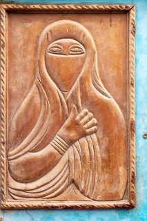 Wood carving depicting a veiled woman, traditional door design with blue border