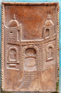 Wood carving of an architectural gate with traditional elements and two towers, traditional door