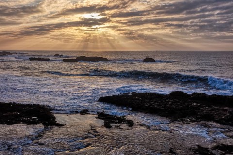Dramatic cloud formations and sunbeams over the sea at sunset