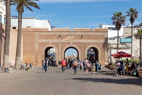 Busy street with access gate and palm trees under a clear sky