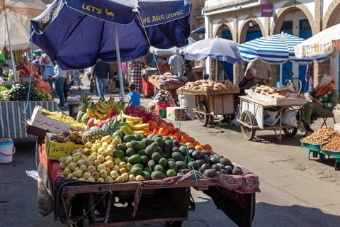 Fertile market stand under umbrellas with a variety of fruits and customers