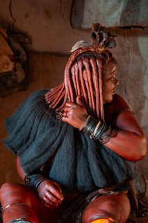 Elderly Himba woman showing her hair and jewelry, in a hut, traditional Himba village, Kaokoveld,
