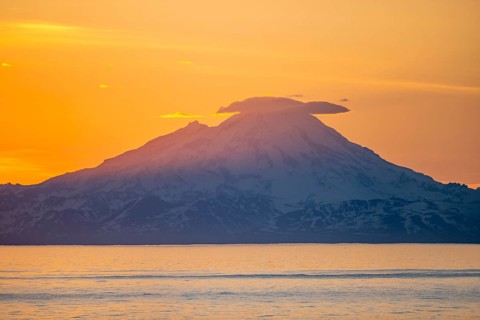 View of Cook Inlet on white mountain peaks of Mount Redoubt at sunset, picturesque golden light of