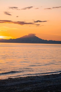 View of Cook Inlet on white mountain peaks of Mount Redoubt at sunset, picturesque golden light of
