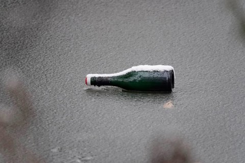 Symbolic picture of garbage in nature, bottle on frozen lake, winter, Germany