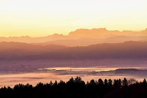 View from Horben of Lake Zug with the city of Cham and Zug covered in fog, behind it the