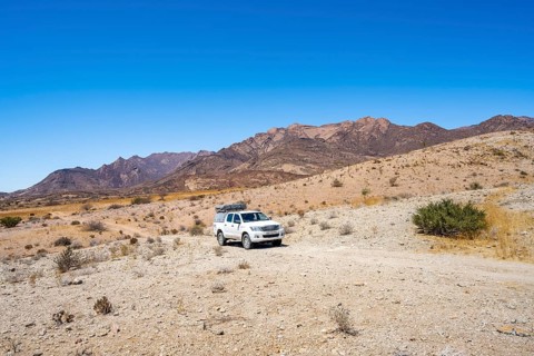 Toyota Hilux off-road vehicle on a sandy track, desert landscape with Brandberg, Erongo,