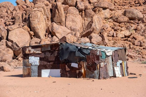 Simple poor huts made of corrugated iron and wood, desert landscape, barren landscape with hills of