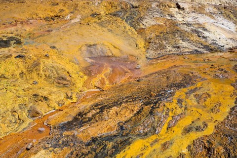 Colourful geothermal formation with yellow and orange earth tones and mineral-rich textures,