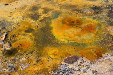 Mineral-rich geological formation in bright orange and yellow tones with rocky surface, geothermal