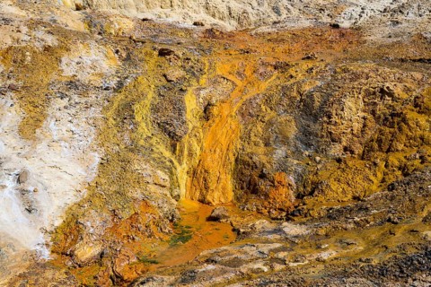 Orange, steep geological formation with volcanic character and rocky texture, geothermal area,