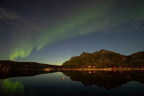 Northern lights are reflected in the fjord in Norway. Aurora Borealis over Festvåg near Bodø,