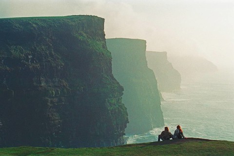 People on the edge of a cliff, there was no fence back then, Cliffs of Moher, County Clare,