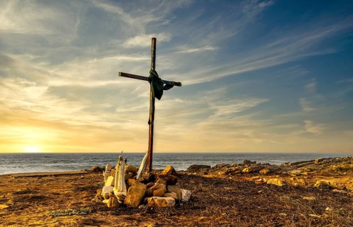 Religious scene, temporary Christian cross on the coast Farol de Cabo Raso lighthouse, São Bras de