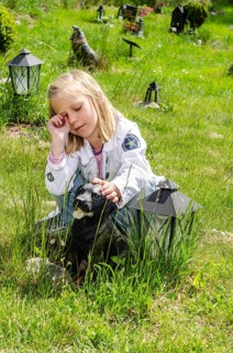 Grieving blonde 7-year-old girl at her dog's grave at pet cemetery in Ystad, Skåne County, Sweden,