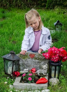 Grieving blonde 7-year-old girl at her cat's grave at pet cemetery in Ystad, Skåne County, Sweden,
