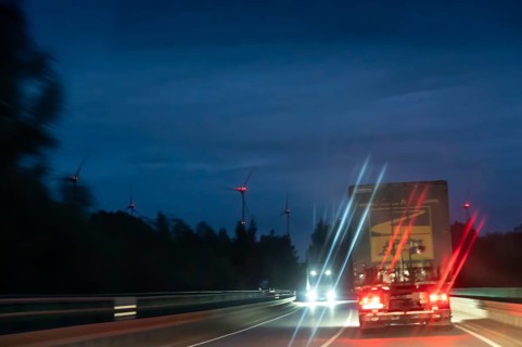 Truck on federal highway at night, wind turbine lights on the left, Schleswig-Holstein, Germany