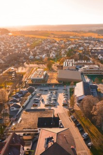 Aerial view of a village at sunset with parked cars and houses, sports center and swimming pool
