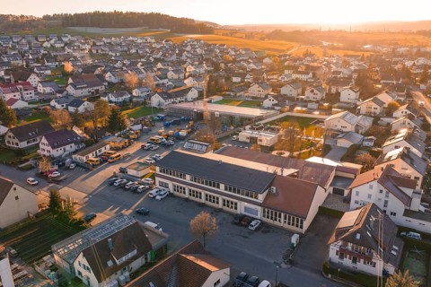 Aerial view of a village at sunset with golden autumn lights and hills in the background, Morof