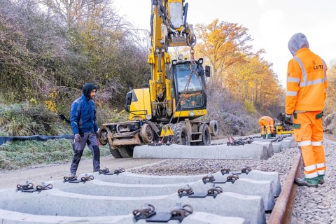 Track construction with a yellow excavator, where workers lay heavy concrete ties, Hermann Hesse