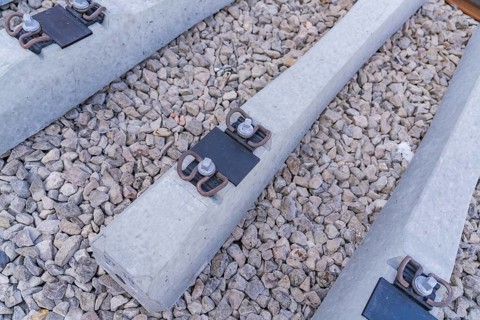 Detailed view of concrete sleepers and their metal fastenings on gravel, track construction of the