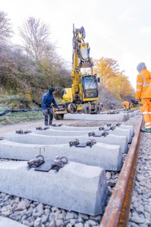 Workers and excavators install new rail ties in an autumn environment, Hermann Hesse Railway track