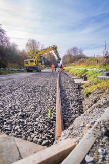 Excavators and workers lay tracks on a construction site on a sunny autumn day, track construction