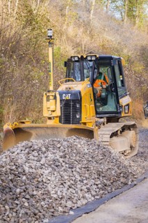 Bulldozer moves gravel on a construction site surrounded by autumn leaves, Hermann Hesse Railway