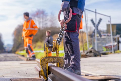 Close-up of a hook on a rail, workers in the background, track construction, Hermann Hesse Railway